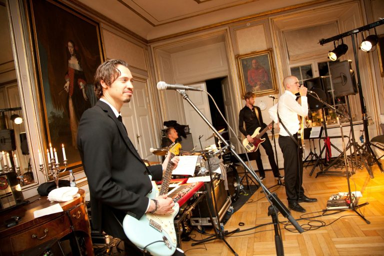 A lively band performance indoors with musicians and instruments on stage.