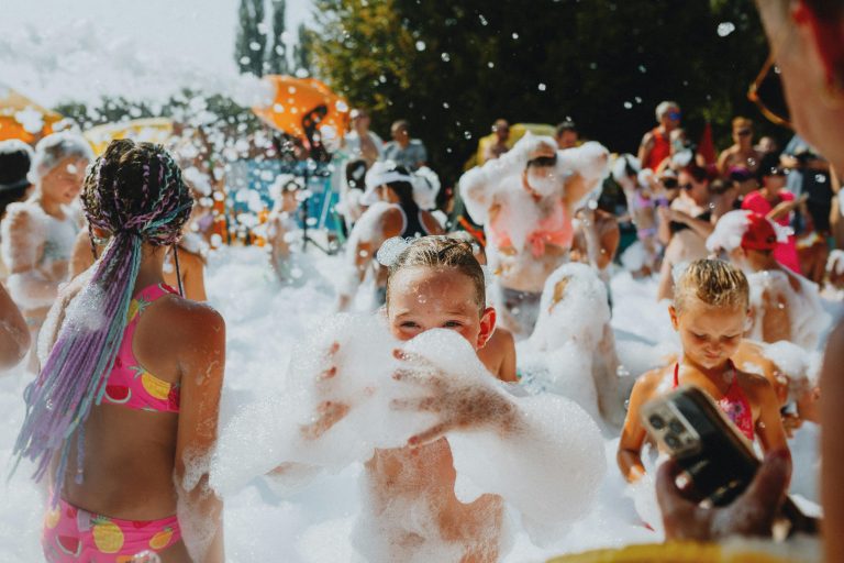A vibrant outdoor foam party with children enjoying bubbles and sunshine, perfect for summer fun.