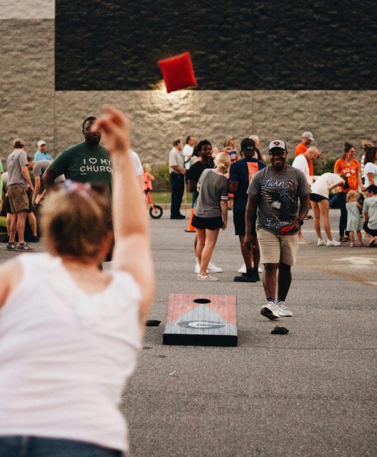 Community members engage in an exciting cornhole game during an outdoor gathering.